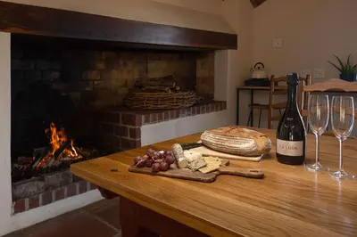a table with wine glasses and cheese and a fireplace at Southwinds Estate in Hermanus
