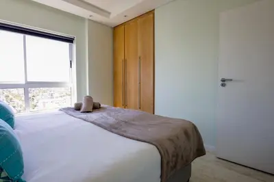a bedroom with a bed with a teddy bear on it at Portico 1006 Beachfront Apartment with Panoramic Views in Cape Town