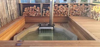 a hot tub in a wooden deck with a fountain at Kwikstertjie in Hermanus