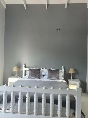 a white bedroom with a white bed with pillows at Kwikstertjie in Hermanus