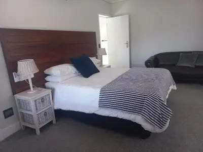 a bedroom with a large bed and a couch at Kwikstertjie in Hermanus