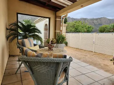 a porch with a table and chairs on a patio at Shalom On The Bay in Cape Town