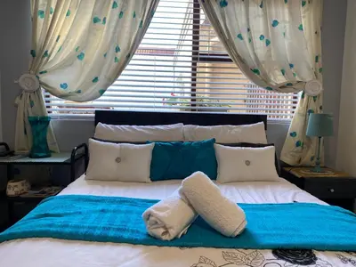 a bed with blue and white pillows and a window at Shalom On The Bay in Cape Town