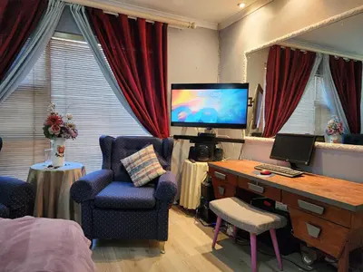 a bedroom with a desk and a tv and a chair at Shalom On The Bay in Cape Town
