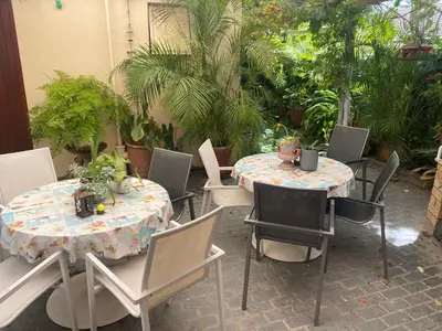 a patio with two tables and chairs and plants at Shalom On The Bay in Cape Town