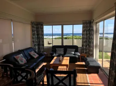 a living room with a couch and a table at La Mer, a beautiful beachfront home in Sandbaai in Hermanus