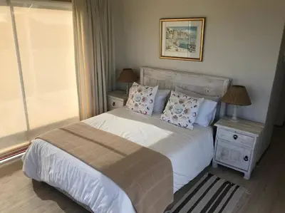 a bedroom with a white bed with pillows and a window at La Mer, a beautiful beachfront home in Sandbaai in Hermanus