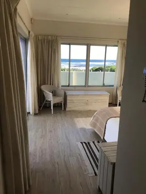 a bedroom with a large window with a view of the ocean at La Mer, a beautiful beachfront home in Sandbaai in Hermanus
