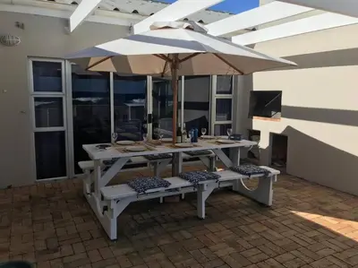 a picnic table with an umbrella on a patio at La Mer, a beautiful beachfront home in Sandbaai in Hermanus