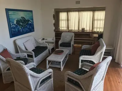 a living room with chairs and a piano at La Mer, a beautiful beachfront home in Sandbaai in Hermanus
