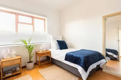 a bedroom with a bed and a large window at Innie Baai Beach House in Cape Town