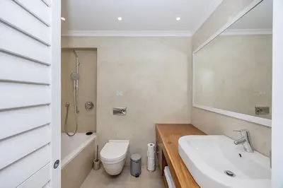 a white bathroom with a sink and a toilet at The Island Beach Villa in Cape Town