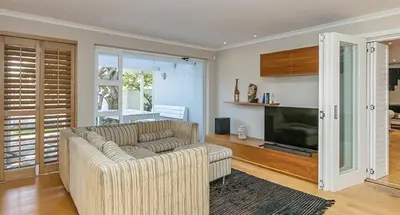 a living room with a couch and a television at The Island Beach Villa in Cape Town