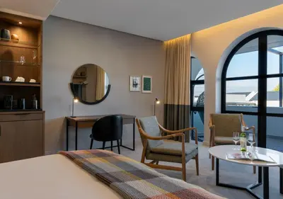a hotel room with a bed and a table and chairs at The Hazendal Hotel and Spa in Stellenbosch