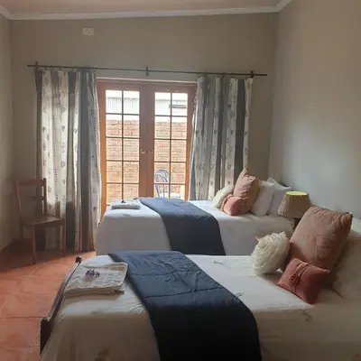 a bedroom with three beds and a window at Irma's farmstay at the Nuy Valley Guesthouse in Nuy