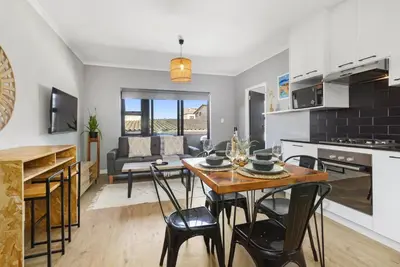 a kitchen and living room with a table and chairs at Cape on Porterfield 5 in Bloubergstrand