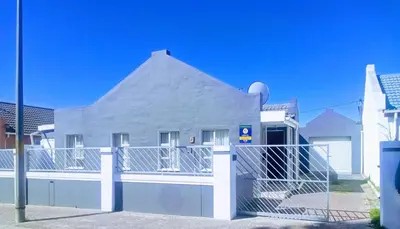 a white house with a fence in front of it at Exclusive Guest House in Cape Town