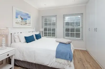 a white bedroom with a bed and two windows at 3-Bed-Mountain View in Hermanus