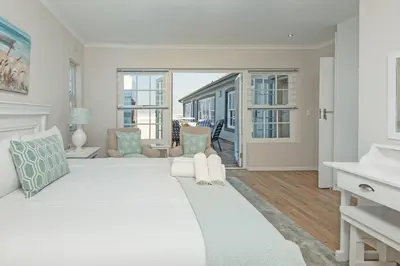 a white bedroom with a large bed and a living room at 3-Bed-Mountain View in Hermanus