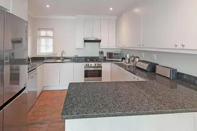 a large kitchen with white cabinets and granite counter tops at 3-Bed-Mountain View in Hermanus