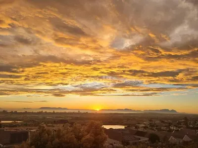 a sunset over a city with the sun setting at Boskloof Eco House I in Somerset West
