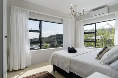 a bedroom with a large bed and large windows at Boskloof Eco House I in Somerset West