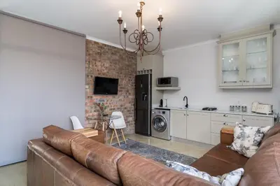a living room with a couch and a kitchen at Boskloof Eco House I in Somerset West