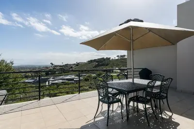 a table and chairs with an umbrella on a balcony at Boskloof Eco House I in Somerset West