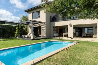 a swimming pool in front of a house at Boskloof Eco House I in Somerset West