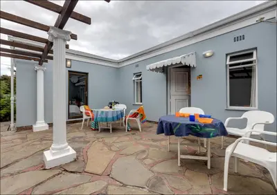 a blue house with a table and chairs on a patio at Island Time in Hermanus
