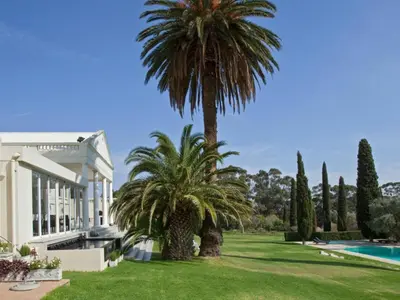 a villa with palm trees and a swimming pool at Retreat at Waterfall Valley in Paarl