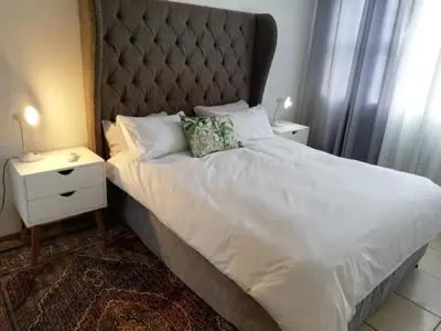 a bedroom with a large bed with a large headboard at Rondebosch East Garlandale STRICTLY HALAAL, fresh garden cottage in Cape Town