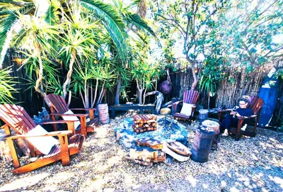 a woman sitting in rocking chairs in a yard at Regent Casa’s in Cape Town