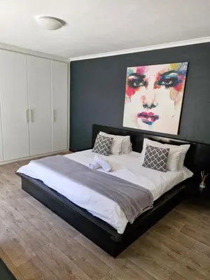 a bedroom with a large bed with a painting on the wall at Regent Casa’s in Cape Town