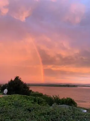 a rainbow in the sky over a body of water at Great spot with a view in Hermanus , South Africa in Hermanus
