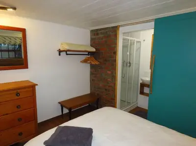 a bedroom with a bed and a bathroom with a shower at De Kelder in Cape Town